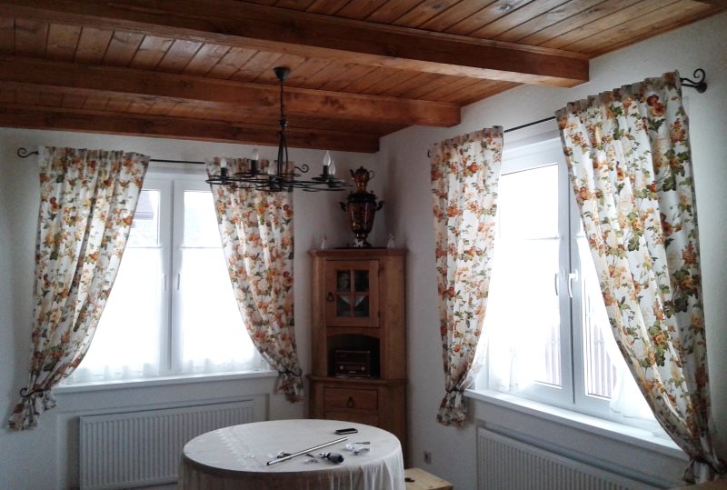 Světlé záclony na oknech haly s dřevěným stropem